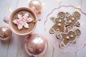top view of gingerbread on glass tray beside a cup of drink and christmas balls